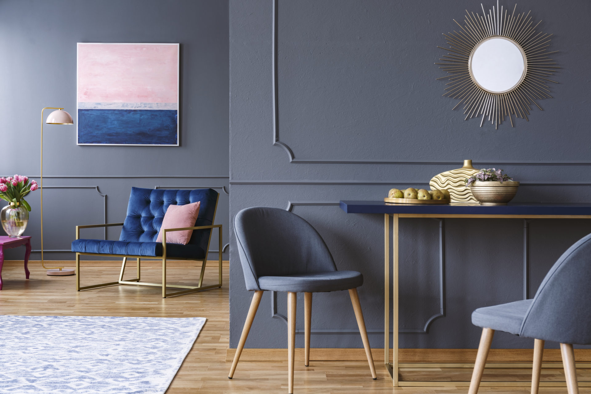 Chair At Table In Modern Grey Apartment Interior With Navy Blue Armchair, Painting And Mirror