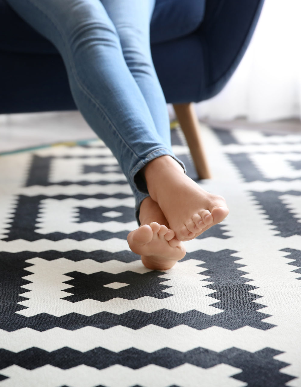 Woman Sitting In Armchair With Feet On Carpet At Home
